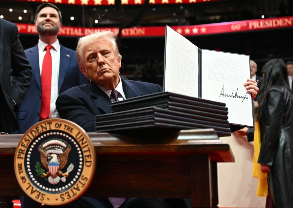 US President Donald Trump signs an executive order during the inaugural parade at Capital One Arena, Washington, DC, on January 20, 2025