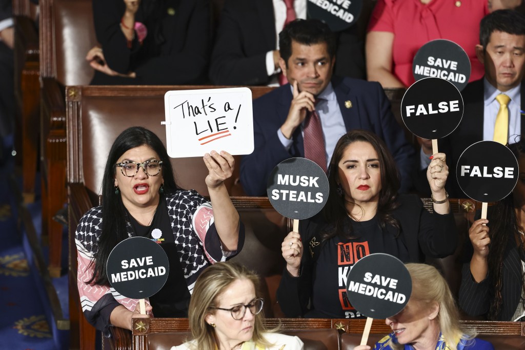 Democratic lawmakers hold signs during President Donald Trump's speech at a joint session of the United States Congress in the US Chamber of Chamber in Washington, DC, USA, March 2025.